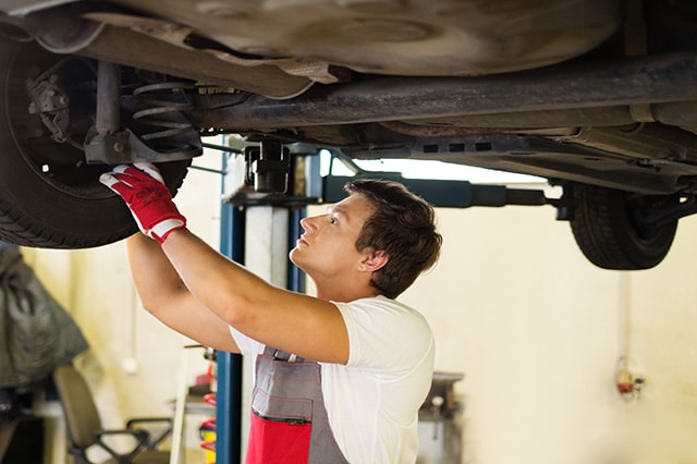 mechanic under vehicle inspecting suspension system