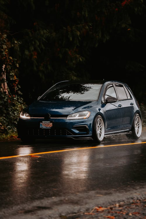 A sleek blue car on a rainy road for a long road trip