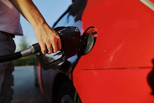 Person refueling a red car at a gas station