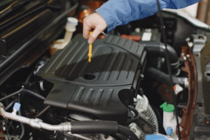 Technician pulling the engine oil dipstick to check oil level and condition during a tune-up