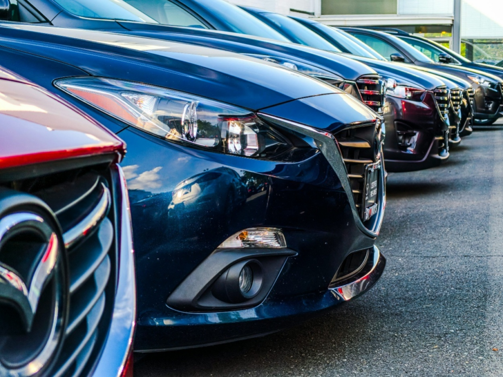 Row of clean, well-maintained vehicles lined up on a dealer lot ready for resale