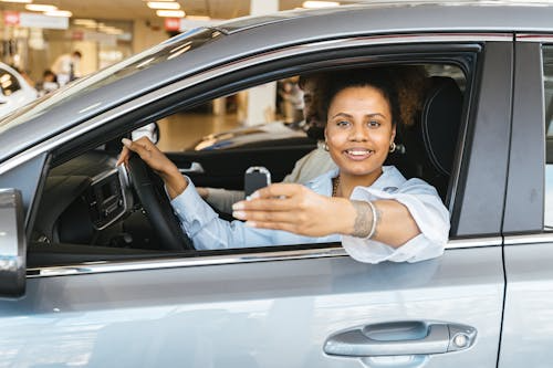 Woman holding a car key while sitting in a car after purchase
