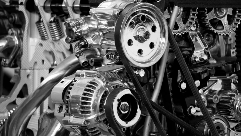 A close-up of a chrome alternator, pulley, and serpentine belt on an engine.