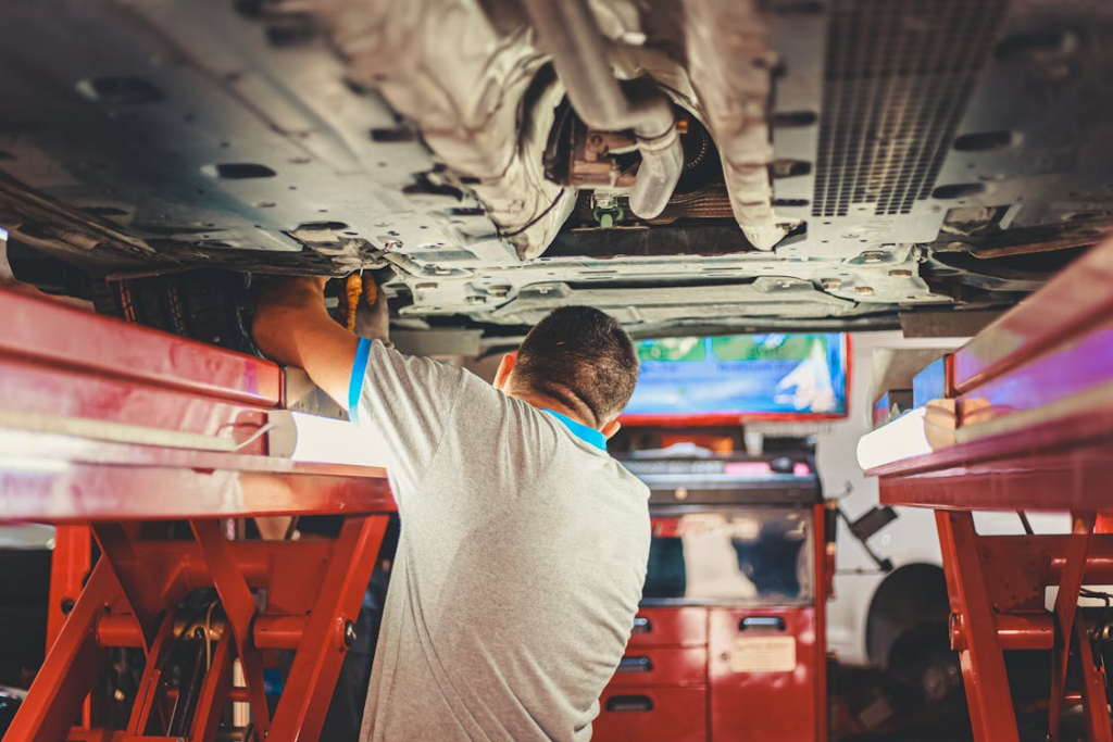 A mechanic inspecting the undercarriage of a vehicle on a lift at an auto repair shop