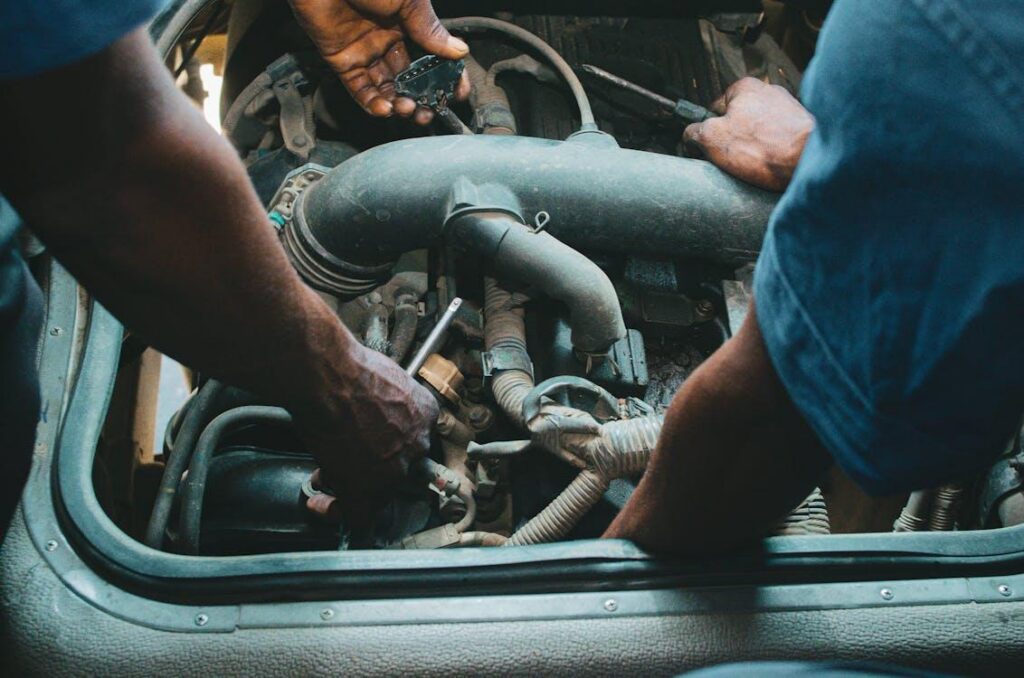 Auto technicians performing engine diagnostics and repair work under the hood of a vehicle