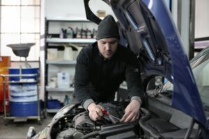 Technician inspecting cooling system components under the hood to diagnose overheating in traffic