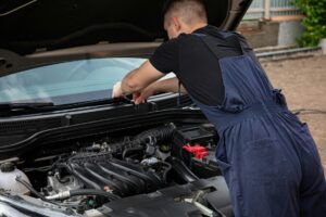 Technician checking a car battery and charging system before battery replacement