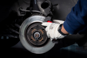 Mechanic working on a car brake system in a workshop setting.