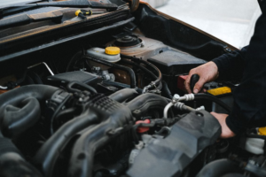 Professional mechanic inspecting an open car engine bay to find causes of a car smelling like gas.